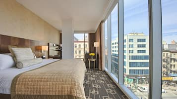 A hotel room with a large bed, a desk, and a view of the city.