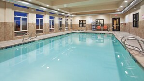 Une piscine à l’eau claire, entourée de murs percés de fenêtres et dotée d’une porte.