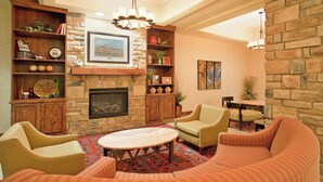 Un salon chaleureux avec une cheminée, des fauteuils confortables et un mur en pierre.