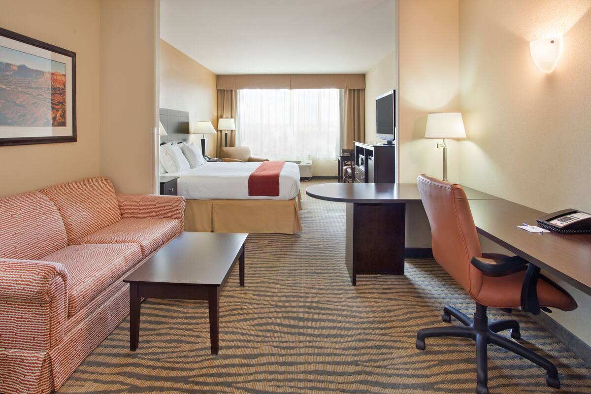 Ein Hotelzimmer mit Bett, Sofa, Schreibtisch und Fernseher.