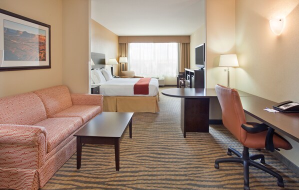A hotel room with a bed, a sofa, a desk, and a TV.