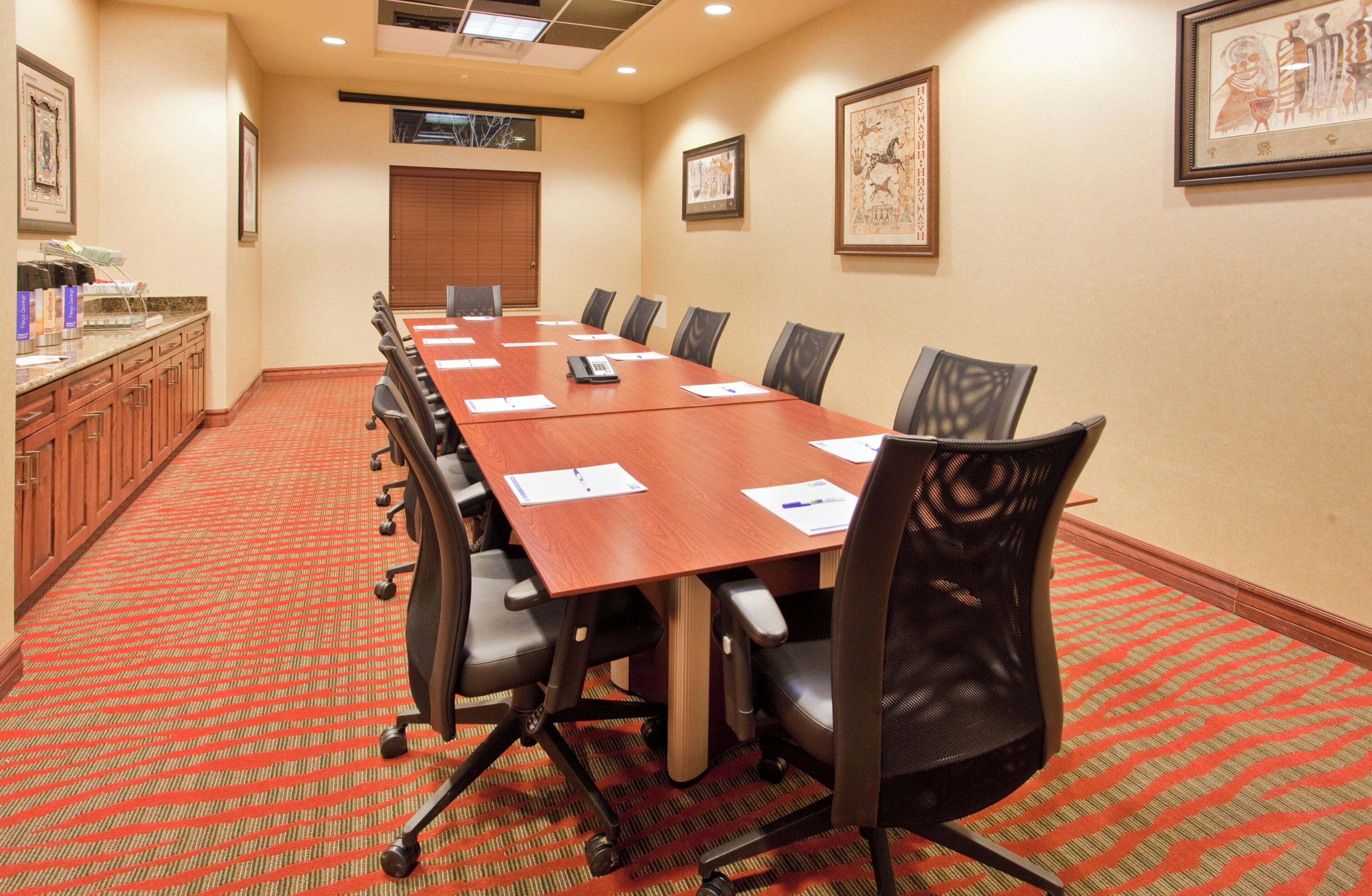 Sala de conferências com uma mesa comprida, cadeiras e um espaço para buffet.