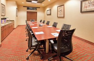 A conference room with a long table, chairs, and a buffet area.