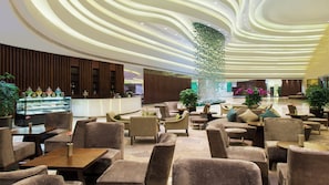 A modern lobby with a curved ceiling, seating area, and a reception desk with a display case. - Holiday Inn Chengdu Xindu by IHG (Chengdu)
