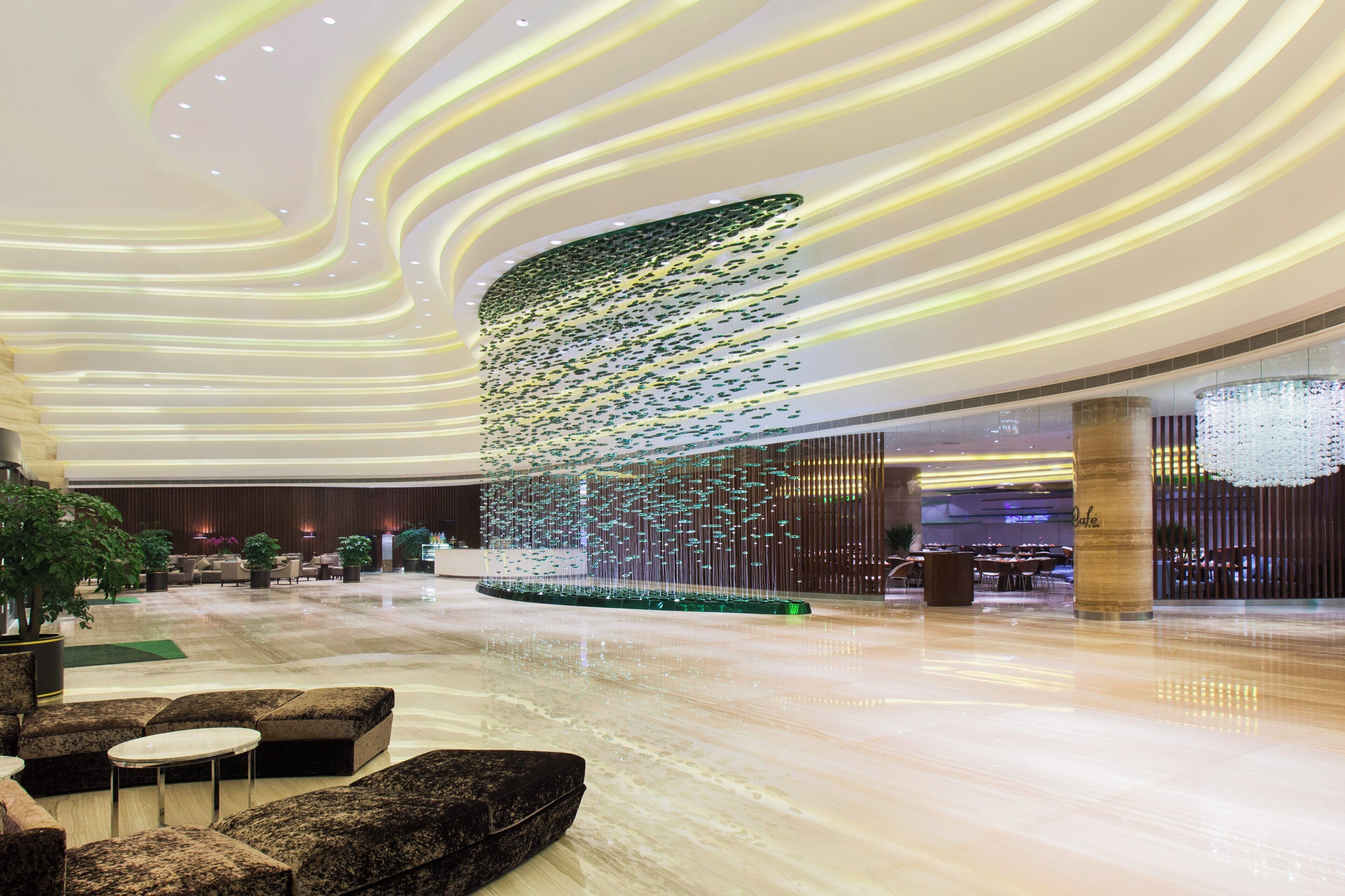 Eine großzügige Lobby mit modernem Design, inklusive einer zentralen dekorativen Lichtinstallation und Sitzbereichen.