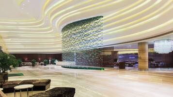 A spacious lobby with a modern design, featuring a central decorative light installation and seating areas.