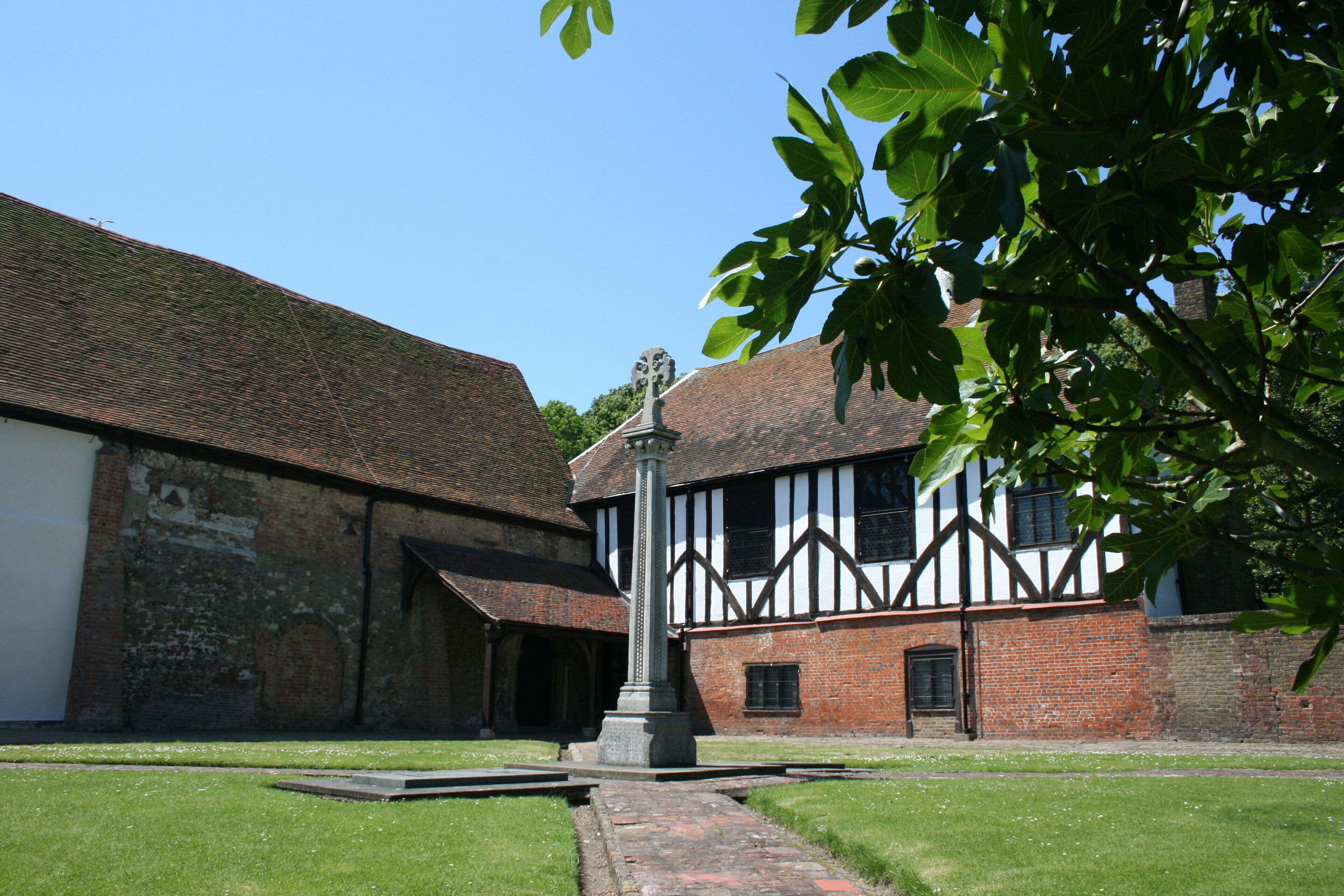 A courtyard with a traditional building featuring a stone wall, a wooden door, and a tiled roof.