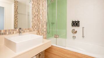 A bathroom with a white sink, a glass shower enclosure, and a white bathtub.