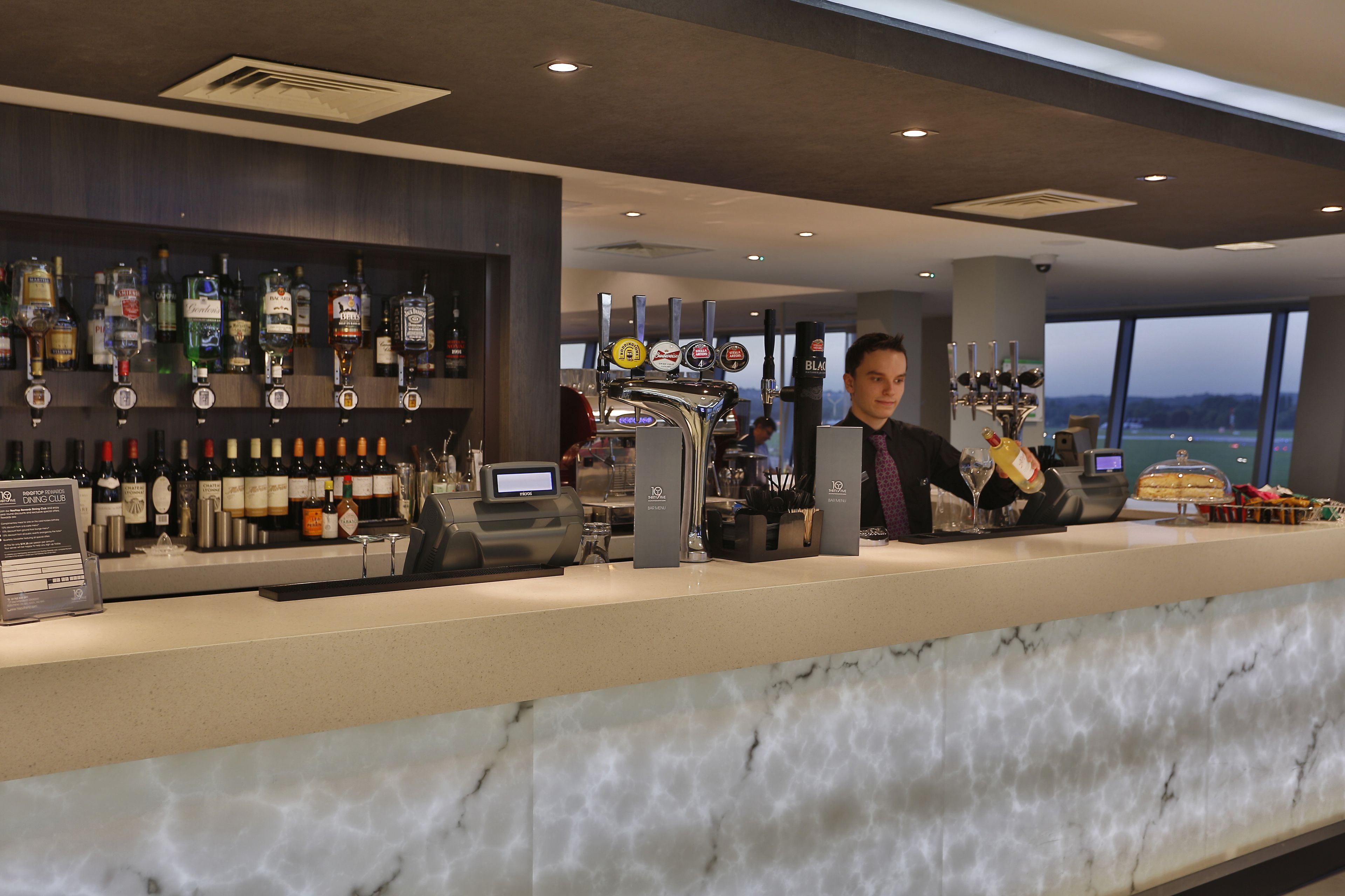 A bar area with a marble countertop, a variety of liquor bottles, and a beer tap.