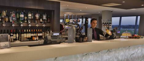 A bar area with a marble countertop, a variety of liquor bottles, and a beer tap.