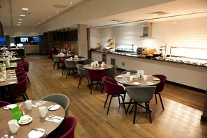 Un restaurant moderne avec un plancher en bois, des tables rondes et des chaises rouges et grises.