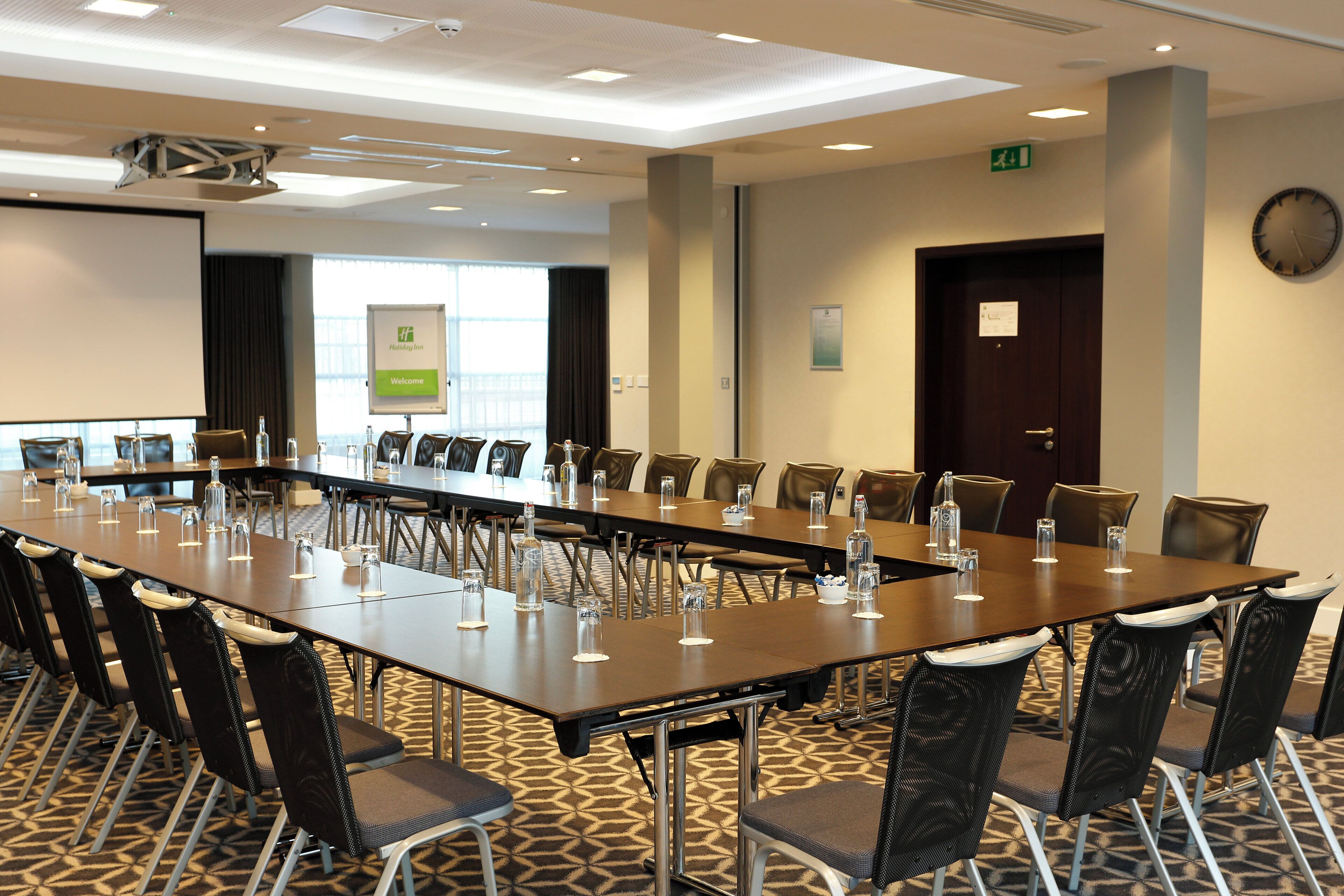 Une salle de conférence équipée d’une longue table, de chaises et d’un écran de projection.