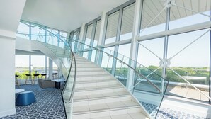 A modern interior with a curved staircase, large windows, and a patterned floor. - Holiday Inn Southend by IHG (Southend-on-Sea)