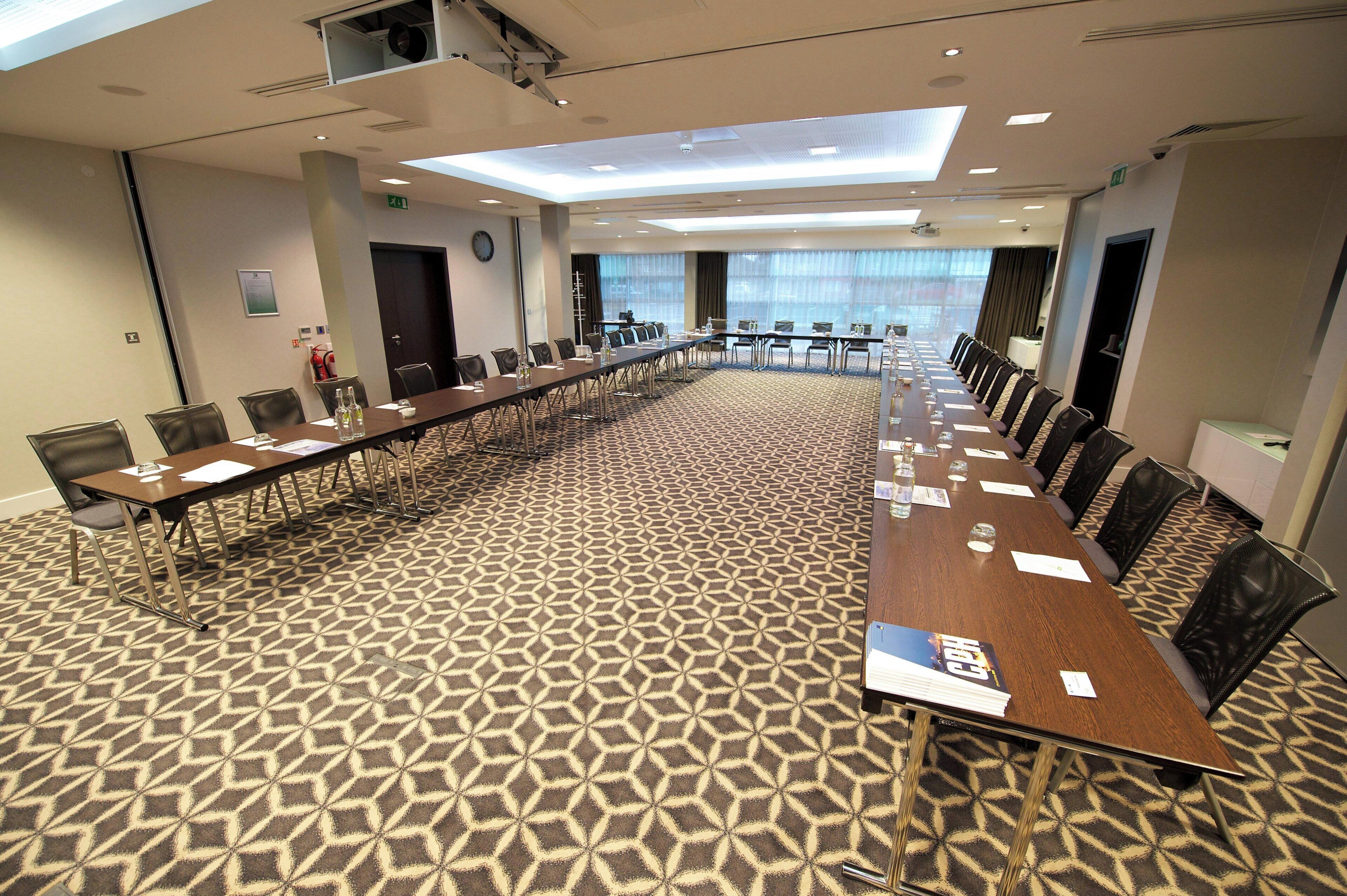 A conference room with a long table, chairs, and a patterned carpet.