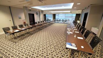 A conference room with a long table, chairs, and a patterned carpet.