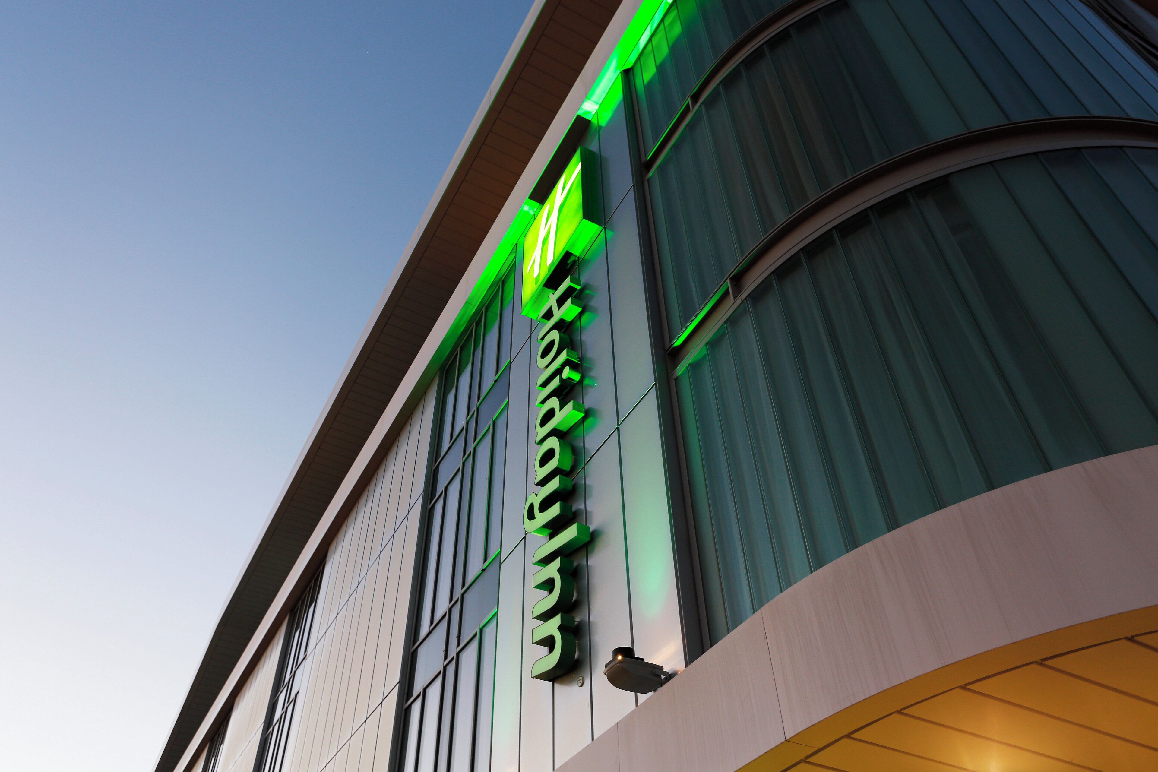 Un edificio dal design moderno, con un cartello verde ben visibile con scritte bianche.