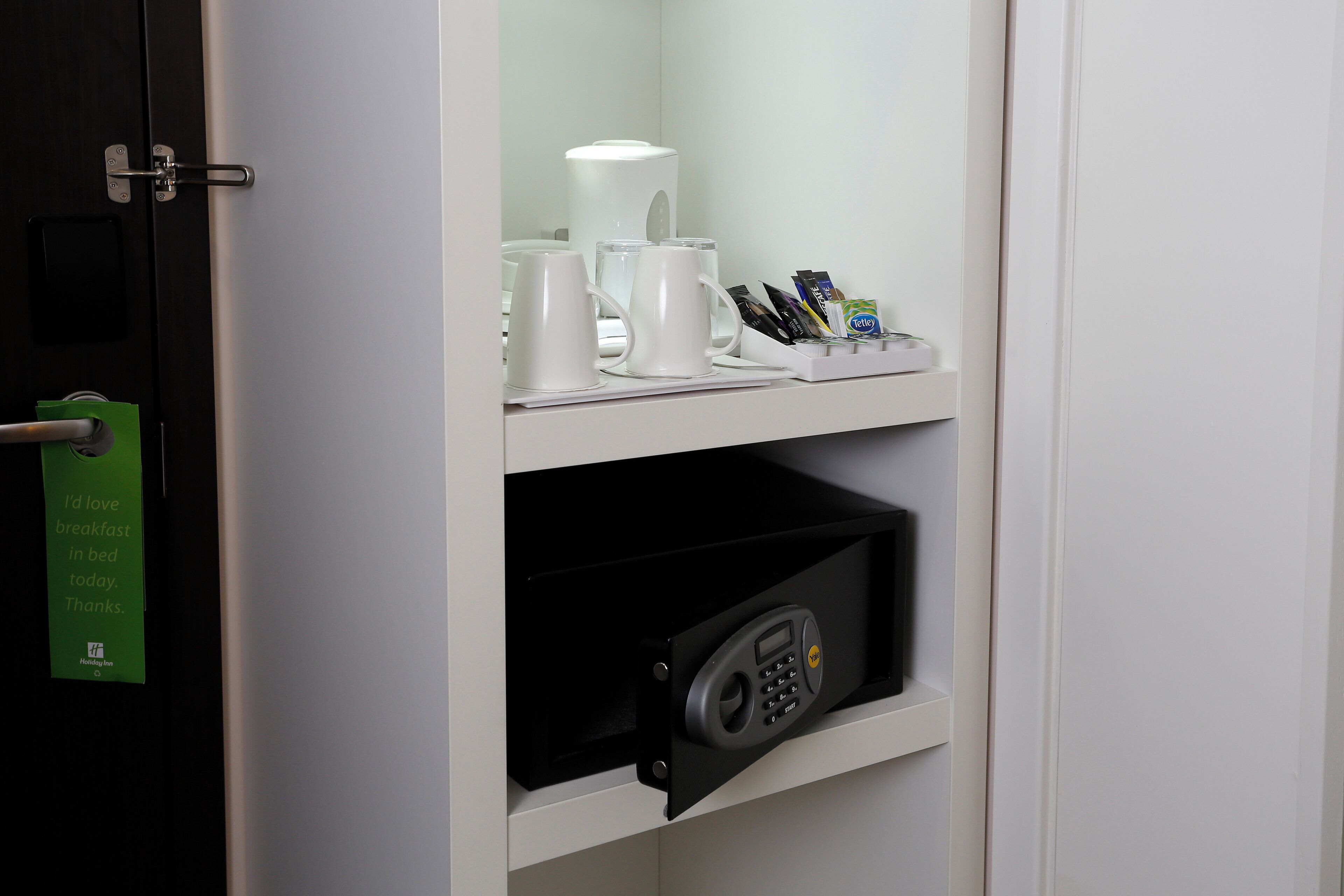 A hotel room with a minibar, a coffee machine, and a safe.