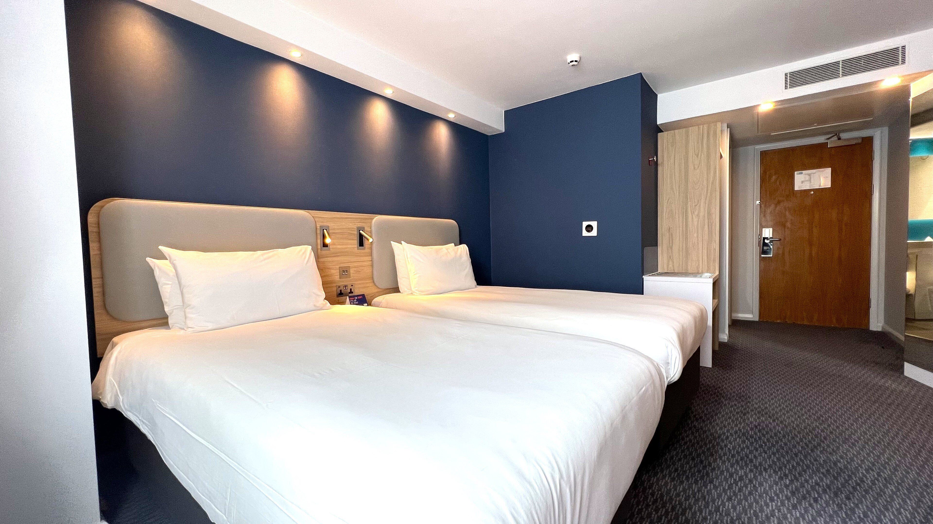 A hotel room with a large bed, a bedside table, a wardrobe, and a bathroom.