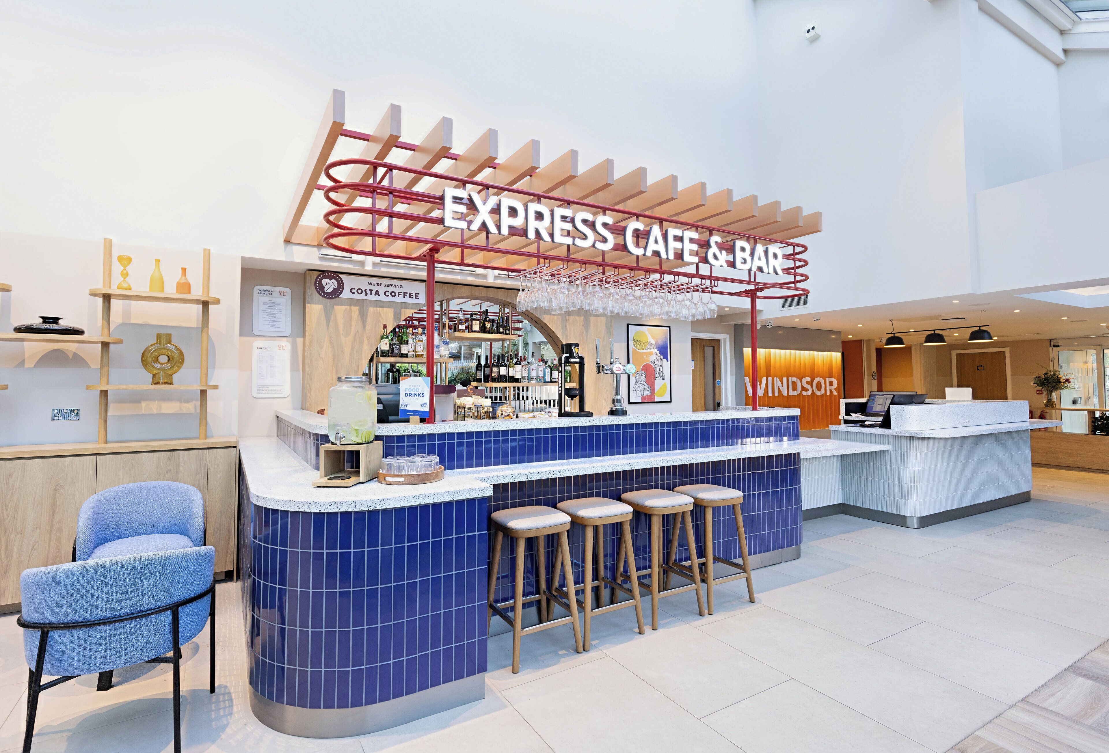 A modern cafe with a blue-tiled counter, bar stools, and a sign reading 'EXPRESS CAFE & BAR'.