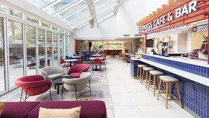 A modern cafe with a glass ceiling, multiple seating areas, and a bar counter. - Holiday Inn Express Windsor by IHG (Windsor)