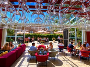 An outdoor dining area with round tables and chairs, surrounded by glass walls and a clear sky. - Holiday Inn Express Windsor by IHG (Windsor)