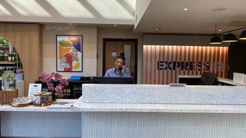 A hotel reception area with a modern design, including a reception desk, a private room sign, and a large 'EXPRESS' sign on the wall.