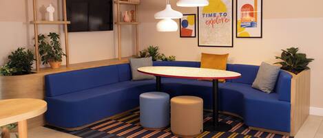 A modern lounge area with a blue sectional sofa, a round table, and a striped rug.