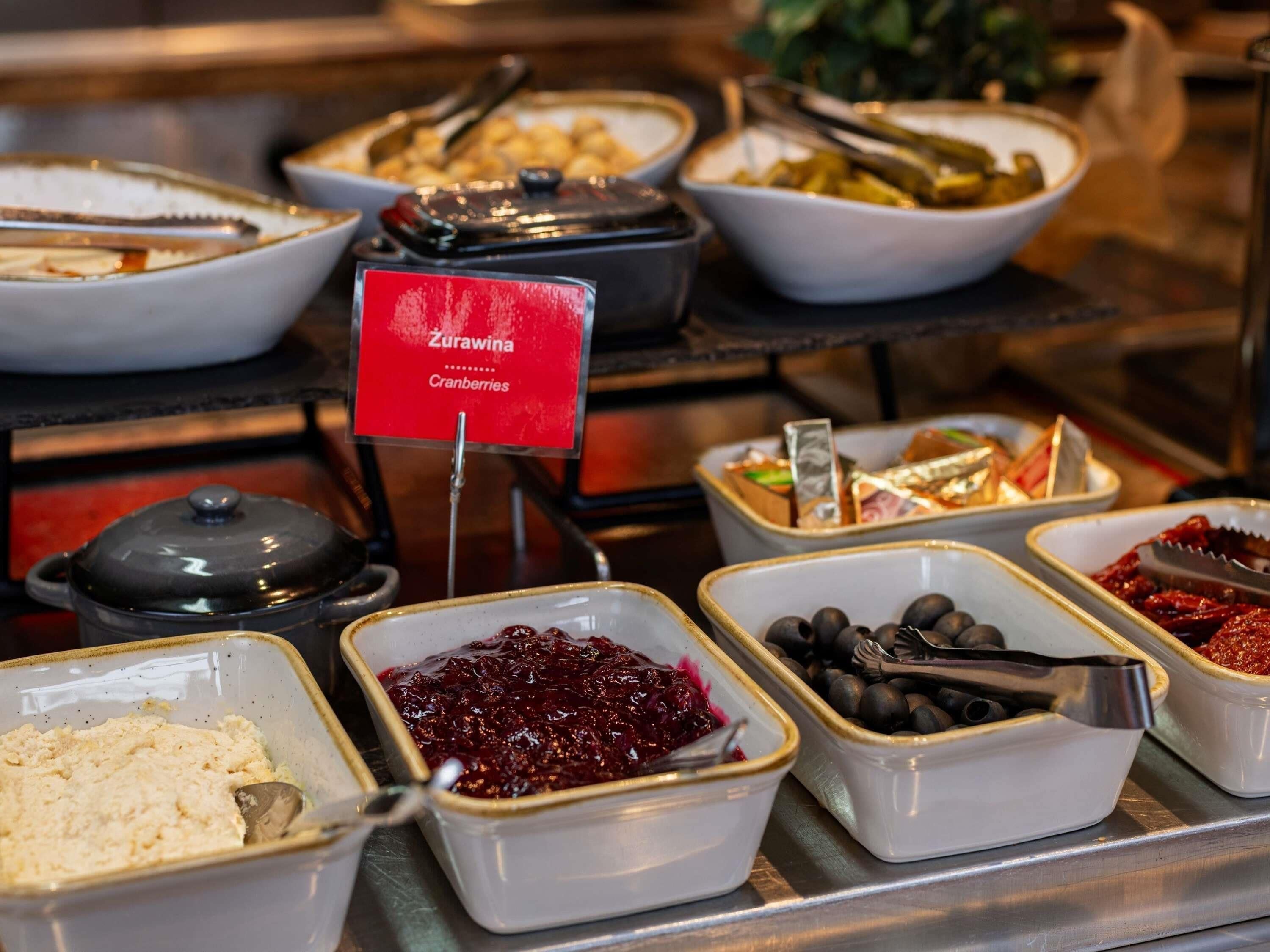 A buffet with various food options including a bowl of cranberries.
