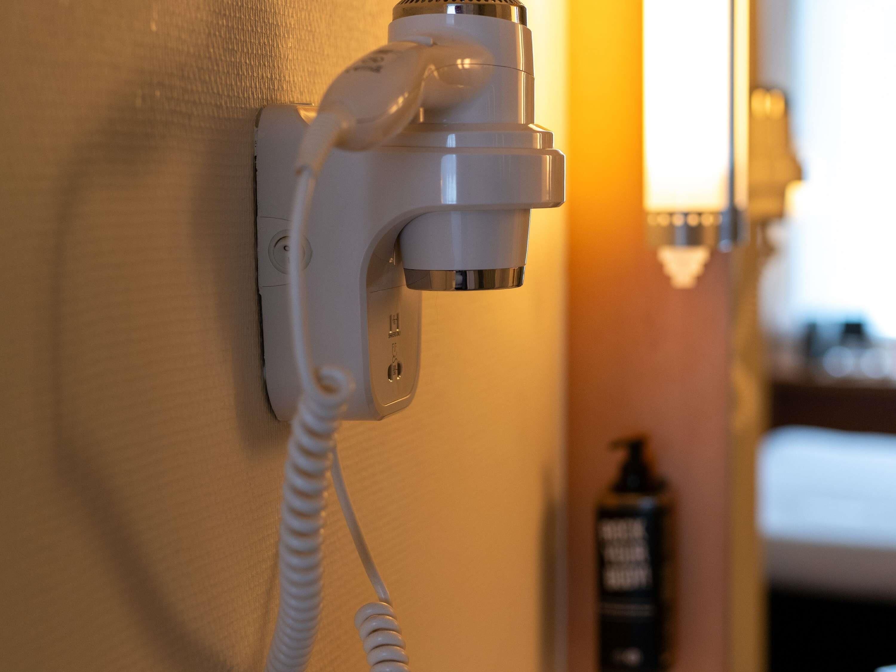 A wall-mounted telephone with a cord, a visible plug, and a switch.