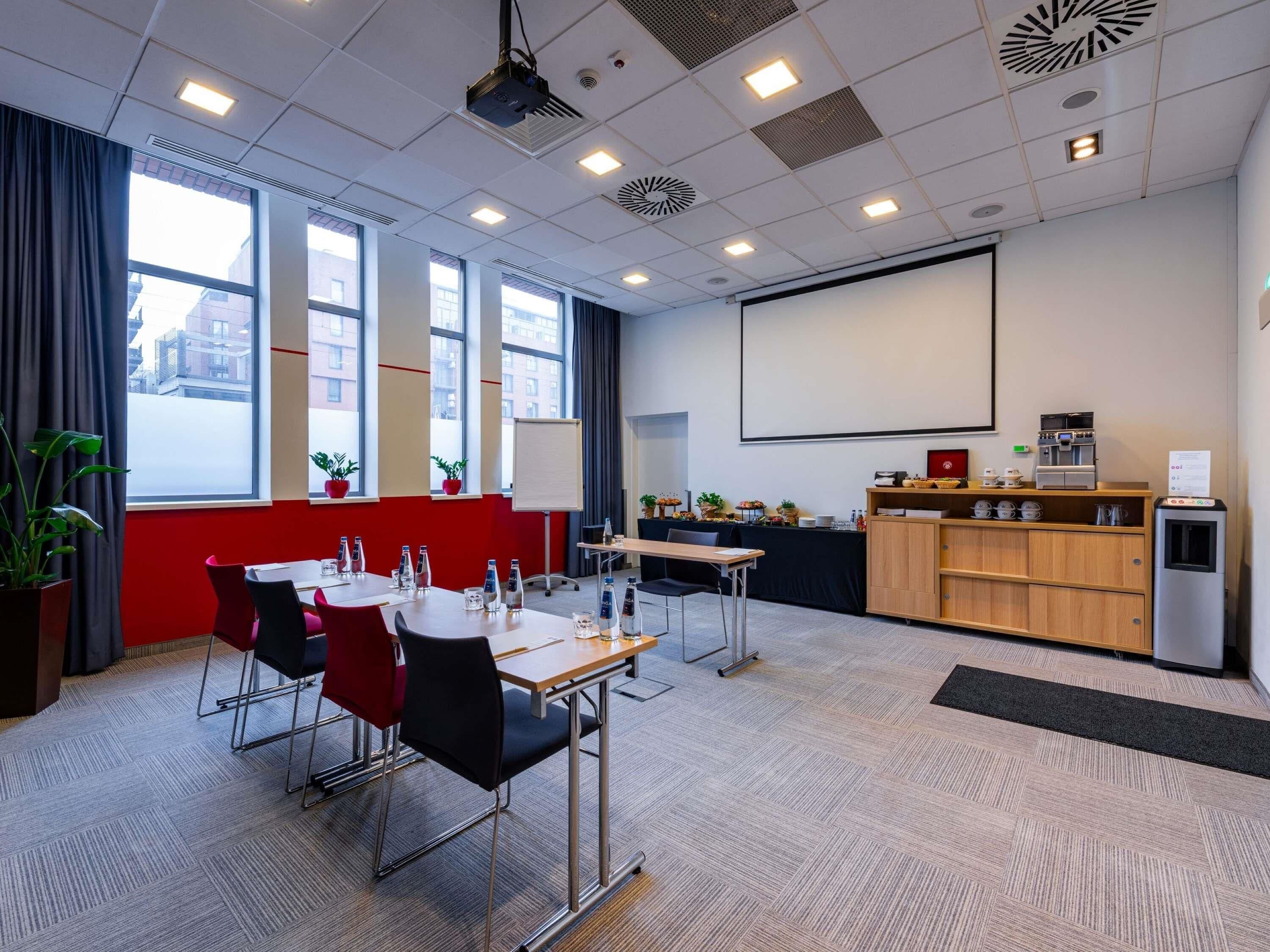 Una sala de conferencias con proyector, una pizarra y un área de café.