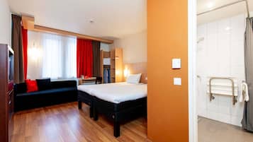 Une chambre d’hôtel comprenant un lit, un canapé, un bureau et un espace douche.