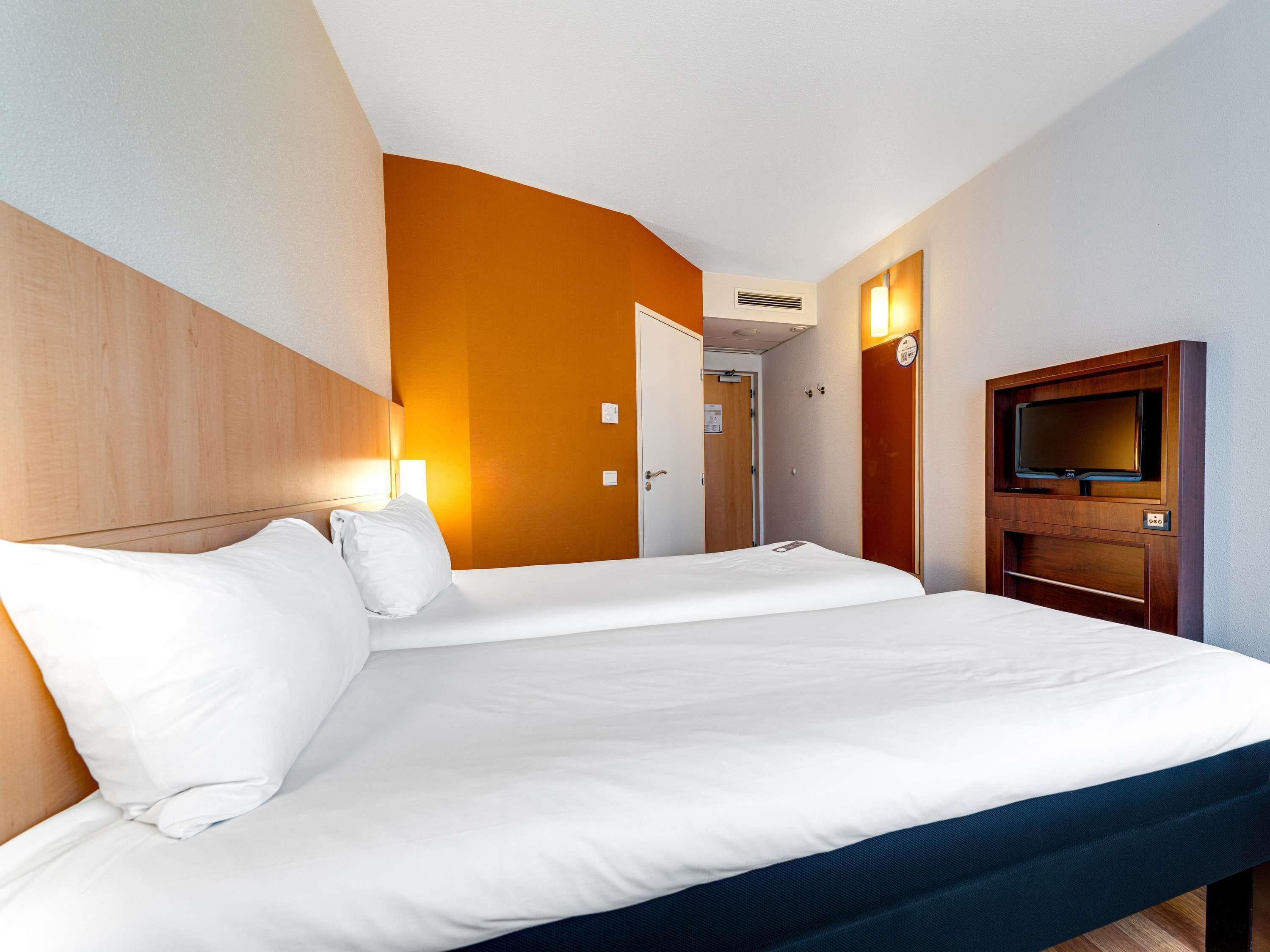Une chambre d’hôtel avec un grand lit, une télévision et une porte donnant sur une salle de bain.