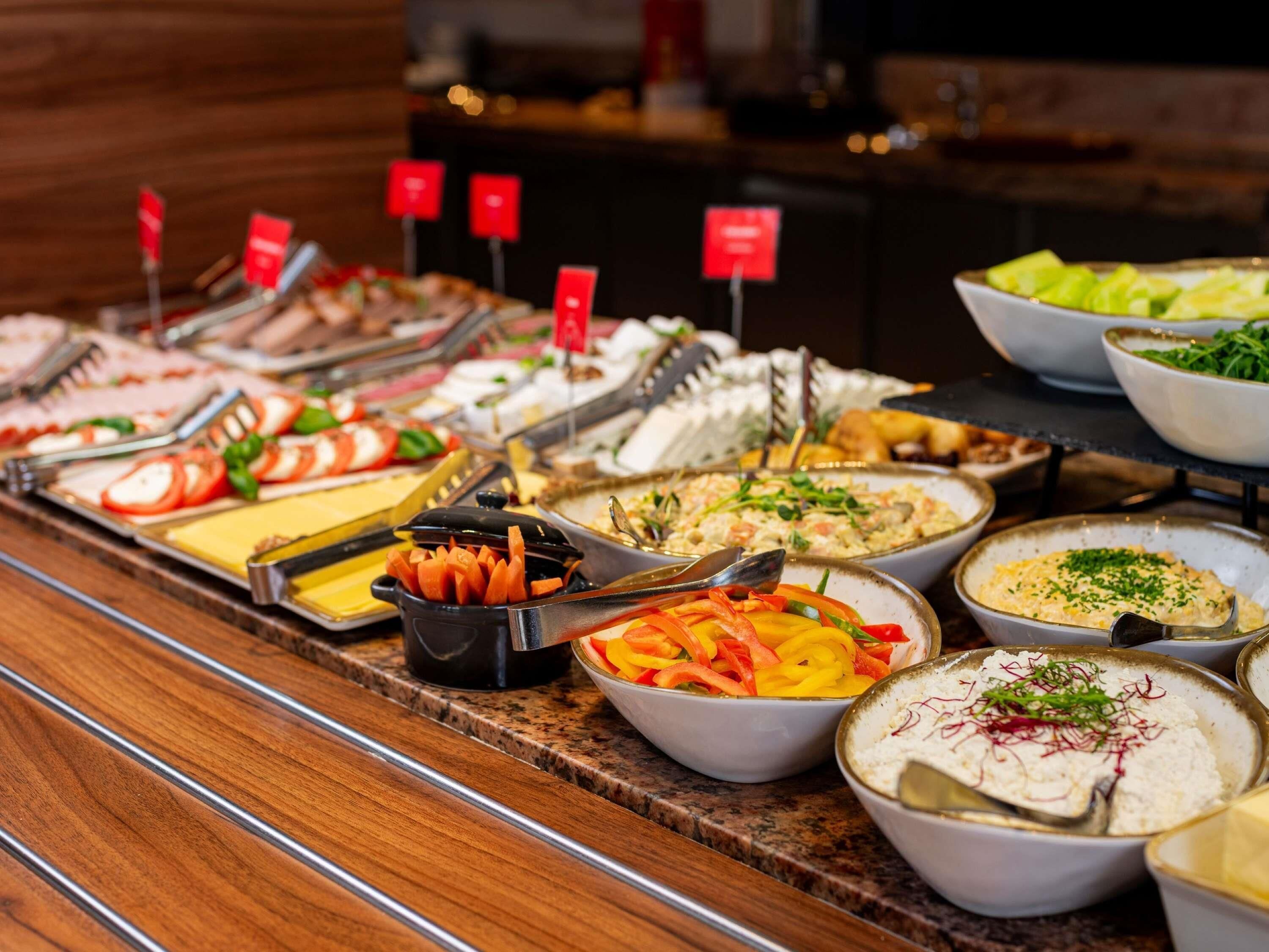 Un bufé con diversas opciones de comida, entre ellas ensaladas, carnes y mariscos.