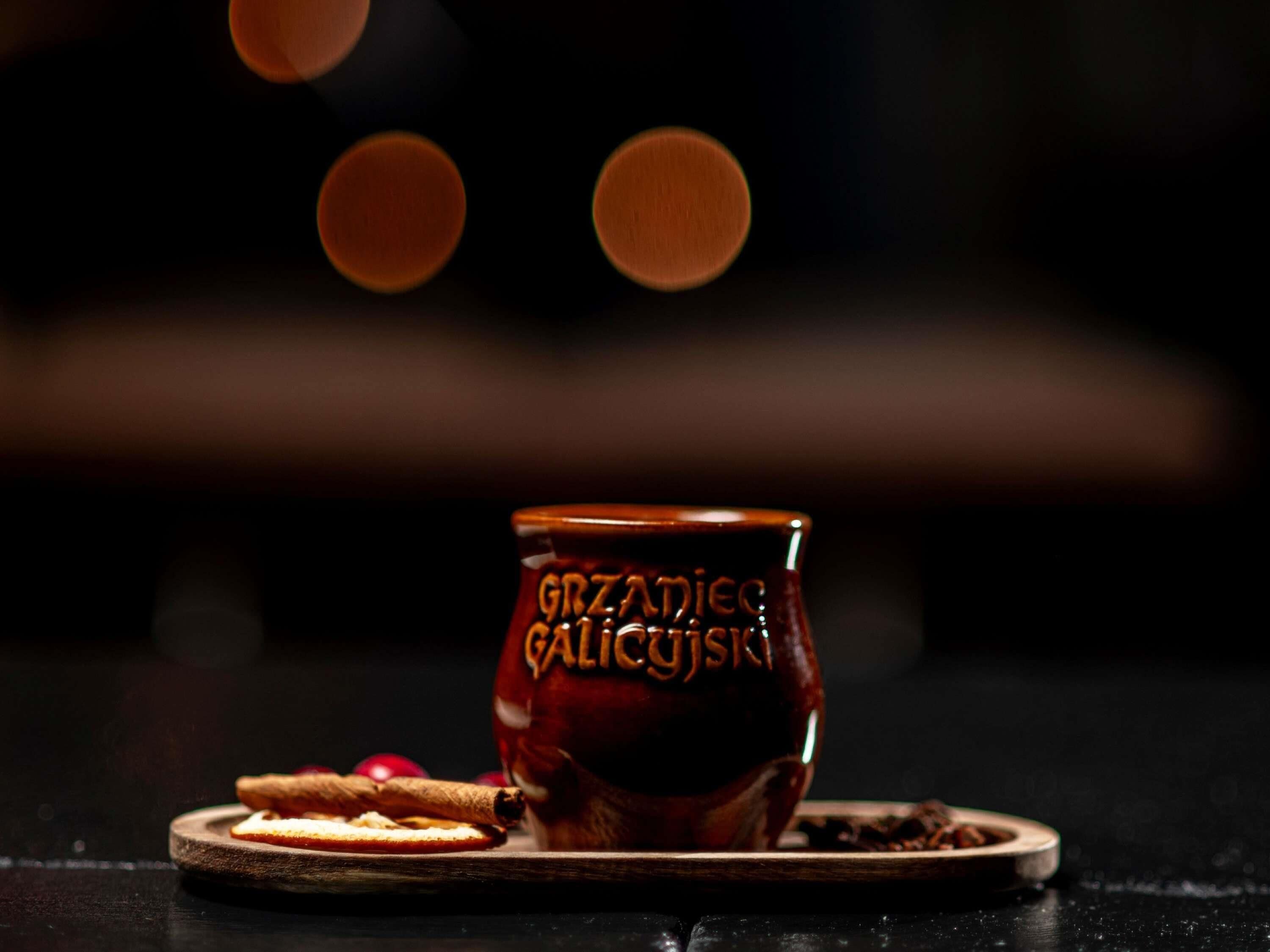 A dark brown ceramic mug with embossed text, placed on a wooden coaster.