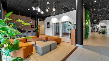 Un vestíbulo moderno con mostrador de recepción, zona de estar y ascensores.