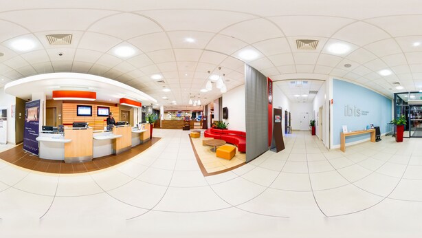 A spacious lobby with a reception desk, seating area, and a blue wall with 'ibis' signage. - ibis Warszawa West Station (Warsaw)