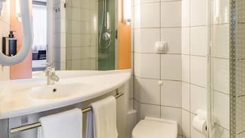 A bathroom with a sink, mirror, towel rack, toilet, and shower.