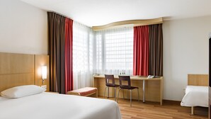 A hotel room with a bed, desk, two chairs, a small table, and a window with curtains. - ibis Warszawa West Station (Warsaw)