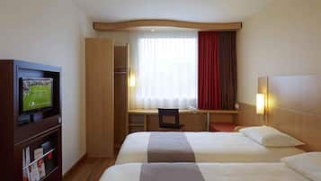 A hotel room with two beds, a desk, a television, and a wardrobe.