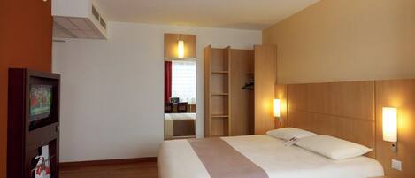 Une chambre d’hôtel équipée d’un lit, d’une télévision, d’une armoire et d’un bureau.