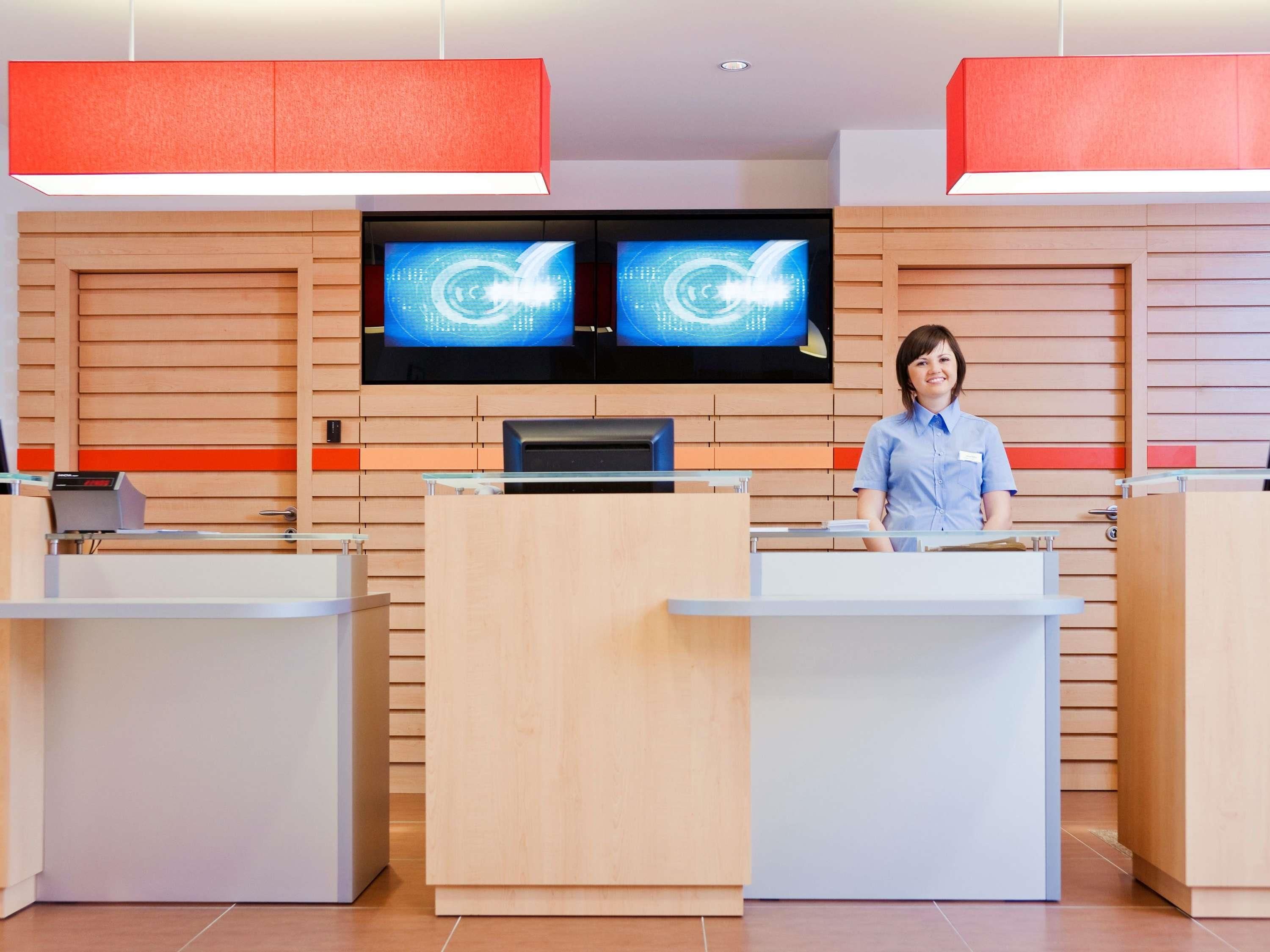 A reception area with a receptionist, two monitors, and a wooden panel wall.