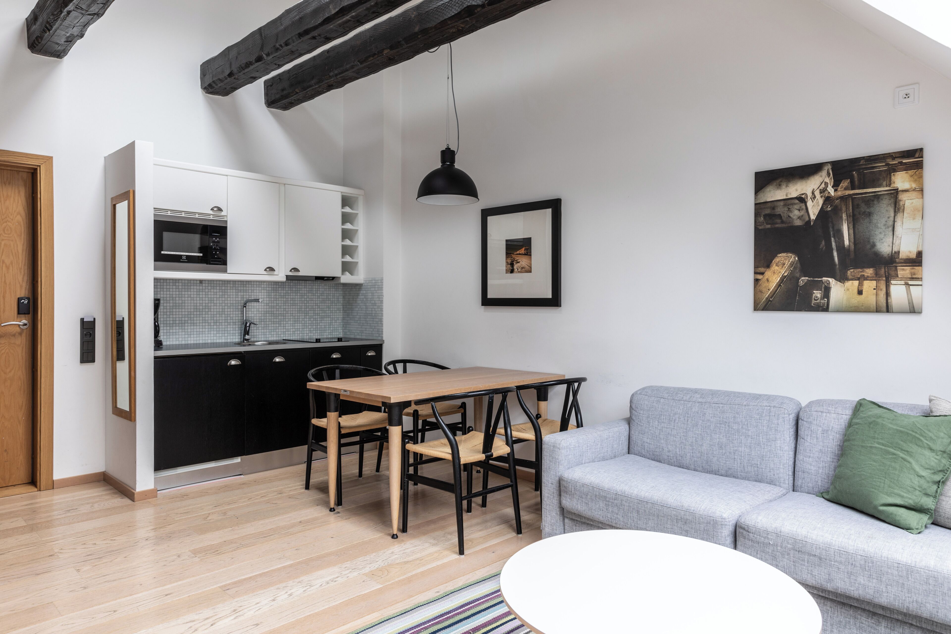 Eine moderne Küche mit Essbereich, einem grauen Sofa und einem Bild an der Wand.
