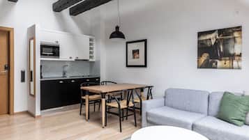 Eine moderne Küche mit Essbereich, einem grauen Sofa und einem Bild an der Wand.