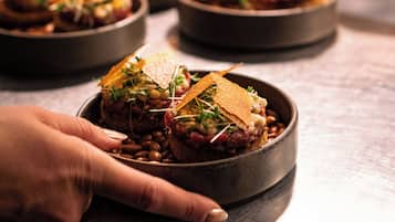 A chef's hand holding a bowl of food with a garnish on top.