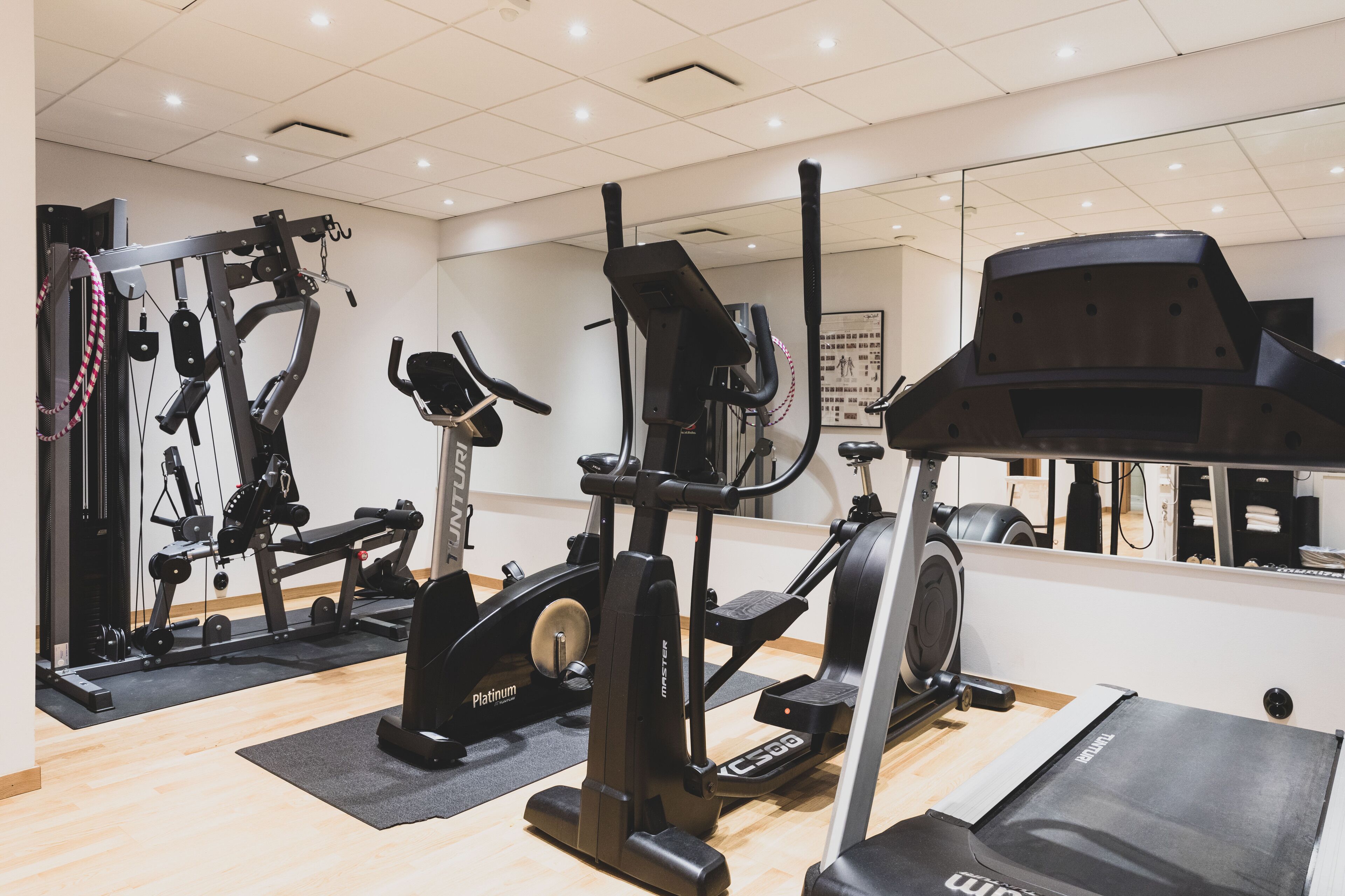 A gym with various exercise equipment, including a treadmill, elliptical, and weight machines.