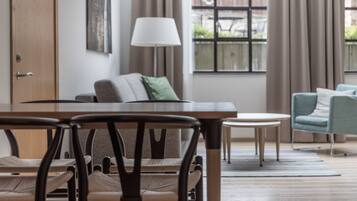 Una sala de estar moderna con una mesa de comedor de madera, sillas, un sofá y una lámpara.