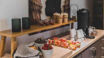 A breakfast bar with various beverages, snacks, and a coffee machine.