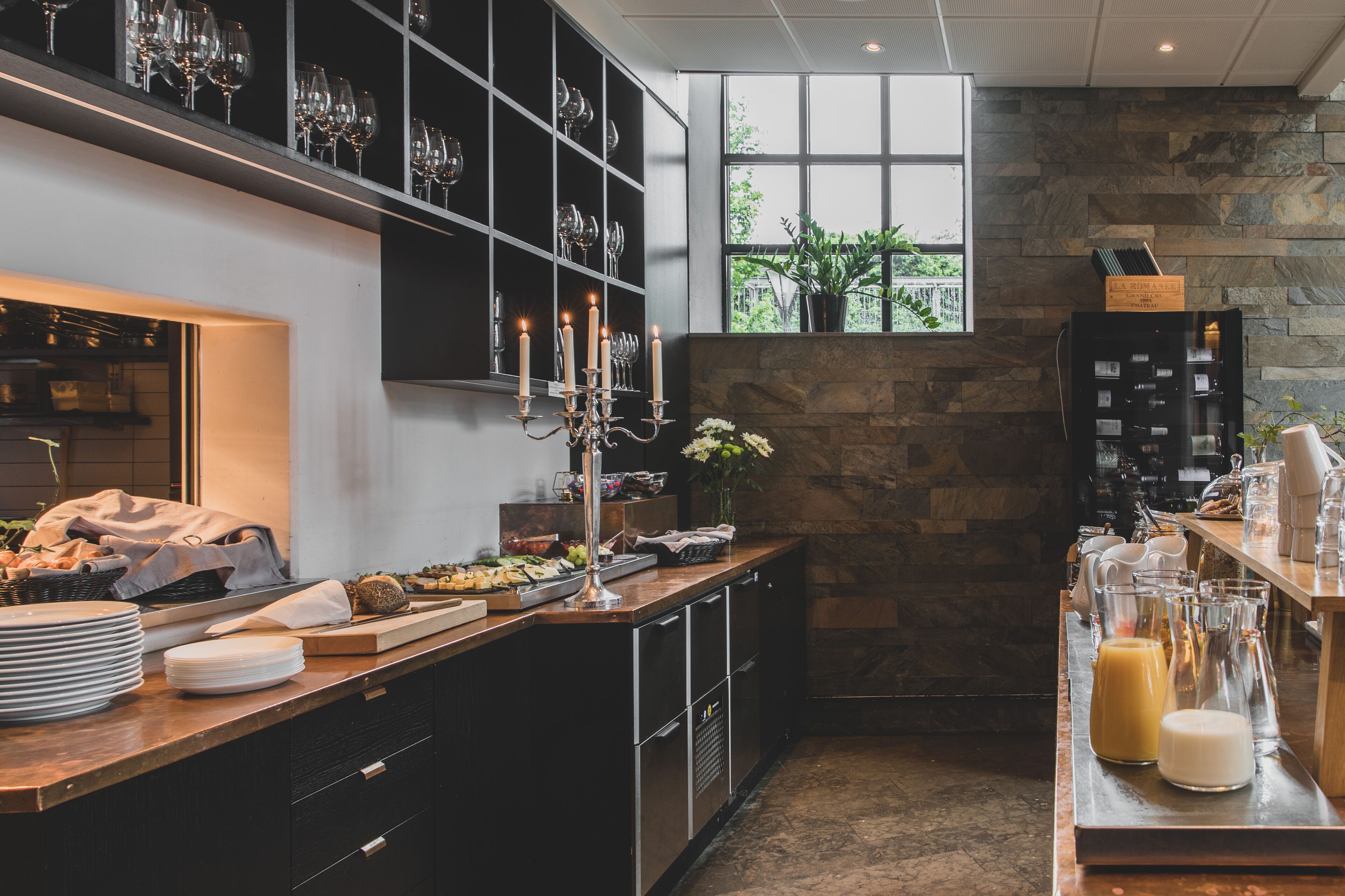 Una cocina moderna con pared de piedra, ventana con vistas y diverso menaje y electrodomésticos.
