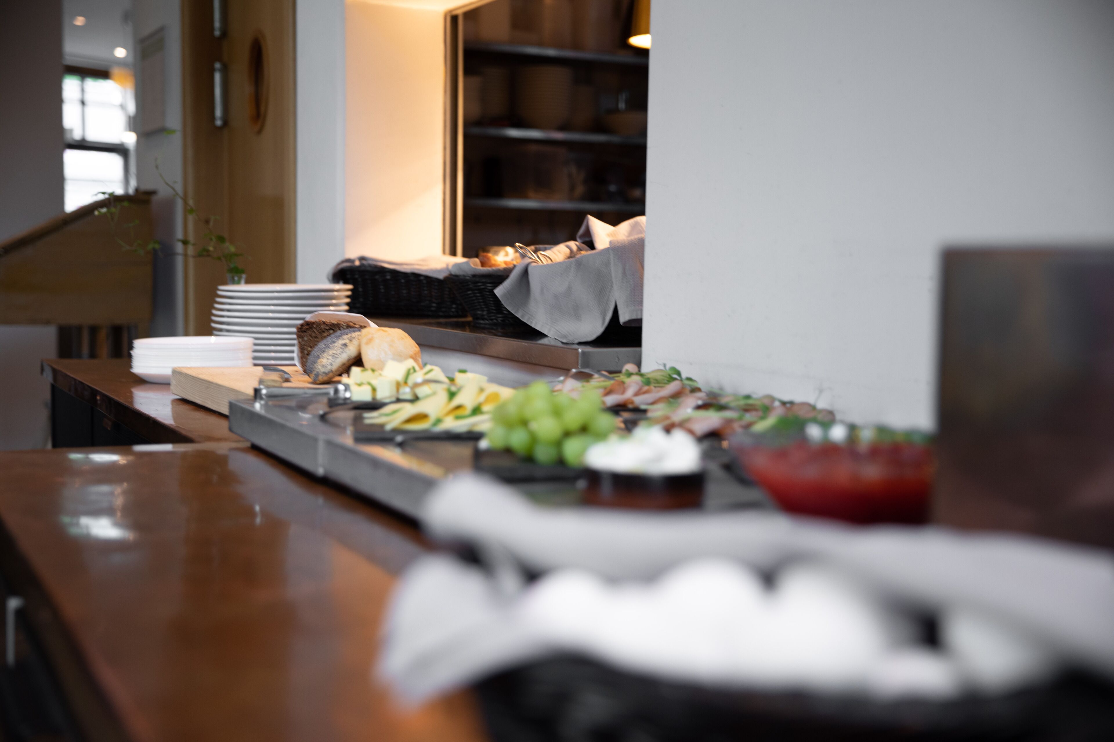 A buffet setup with various food items and a stack of plates.