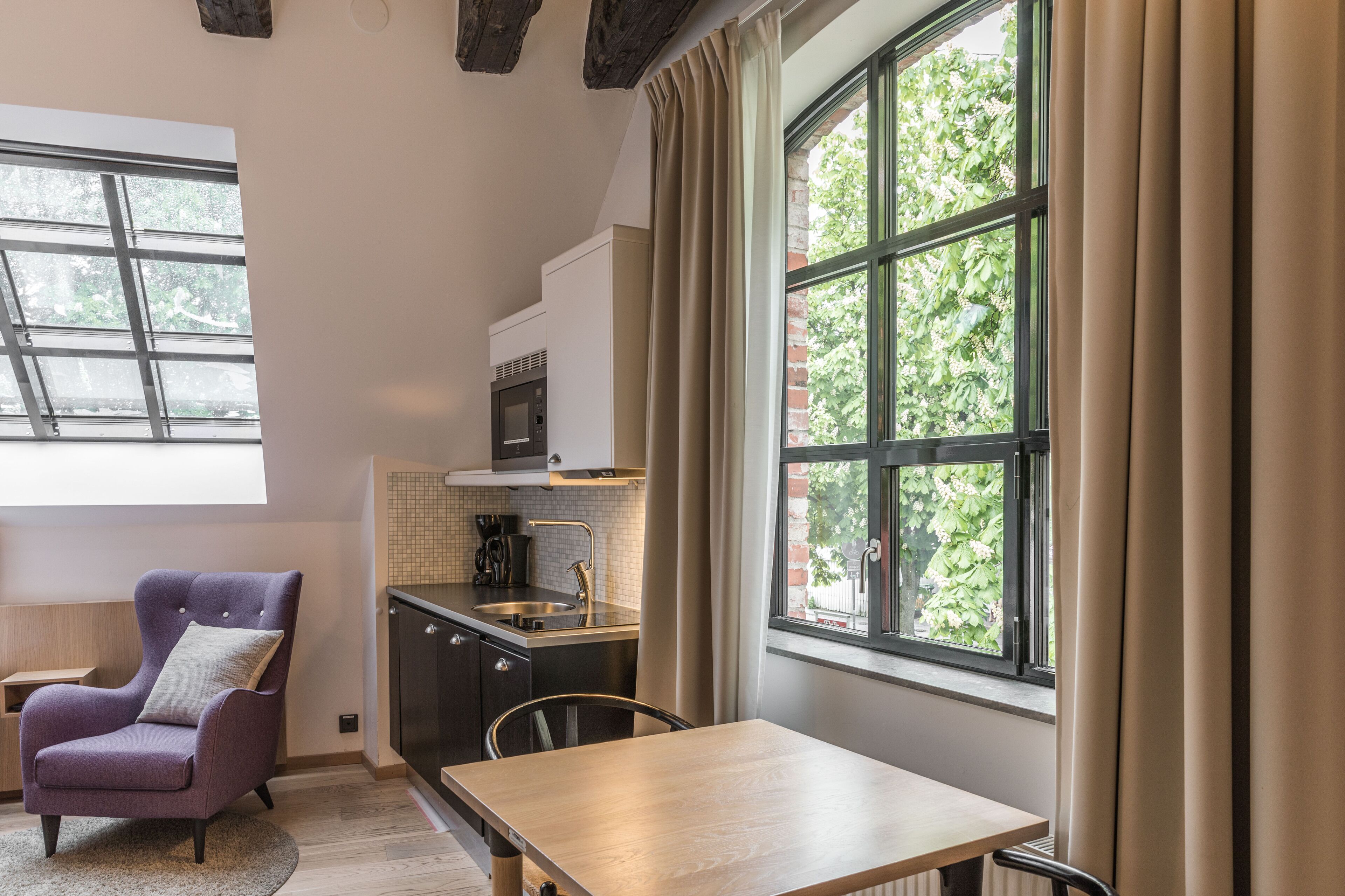 Una cocina moderna con horno empotrado, lavamanos y ventana con cortinas.